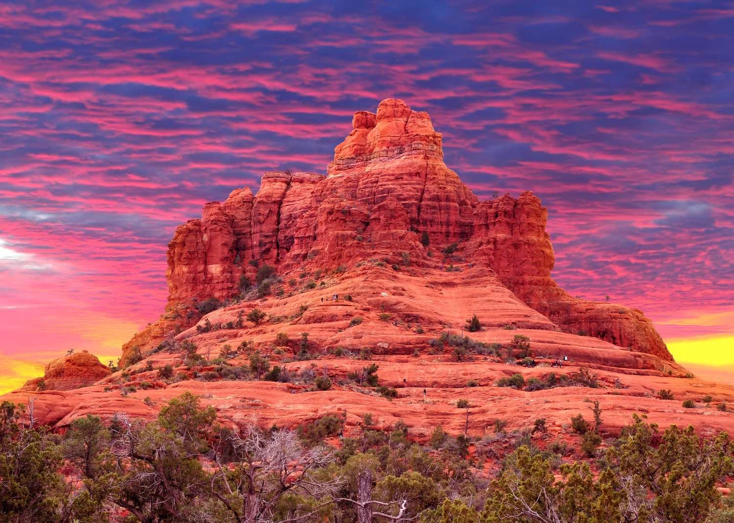 Bell Rock in Sedona glowing red under a pink and purple sunset sky