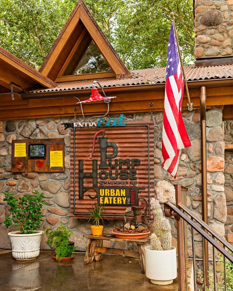 Exterior of Pumphouse Station Urban Eatery & Market in Sedona, featuring rustic stone walls, American flag, plants, and the restaurant sign.