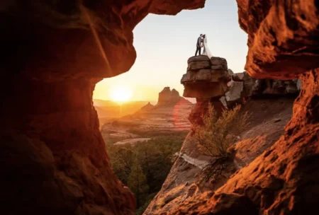 Visit Sedona, Arizona: A Top Global Travel Destination for 2027. Couple framed by a red rock arch at sunset